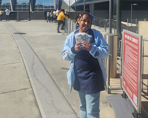 A smiling young girl delivers tracts in front of the Mercedes Stadium in Atlanta, Georgia. 