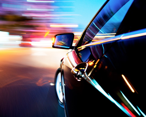 Fast driver of a sports car at night looking into side mirror.
