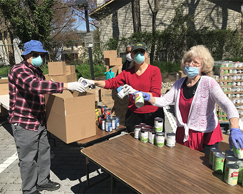 Volunteers of Adventist Community Services Greater Washington sort cans while wearing gloves and masks. 