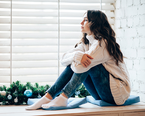 stock photo of young woman looking out window xmas