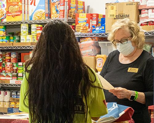 Young student speaking to older woman standing in a food pantry