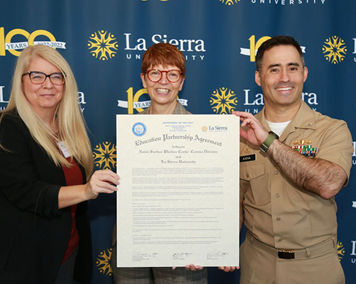 La Sierra University Provost April Summitt, La Sierra University President Joy Fehr, and NSWC Corona Commanding Officer Capt. Michael Aiena hold a commemorative version of the Educational Partnership Agreeement after signing it on Nov. 14. 