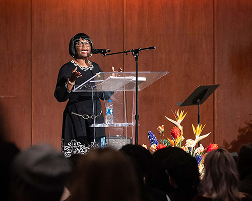 Sarah Collins Rudolph, survivor of 1963 Birmingham Church bombing, standing at a podium with a mic sharing her story in front of a crowd