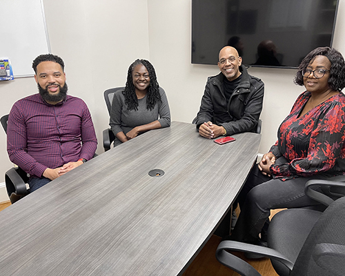 2)	Some of the major players behind the Capitol Hill Counseling and Resource Center, two men and two women of African-American descent, seated around a large table in a conference room