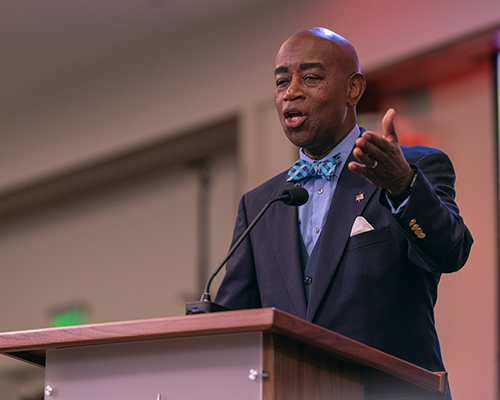 Black man standing behind a podium, smiling