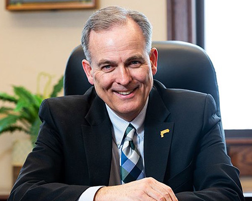 Man in suit smiling towards camera.