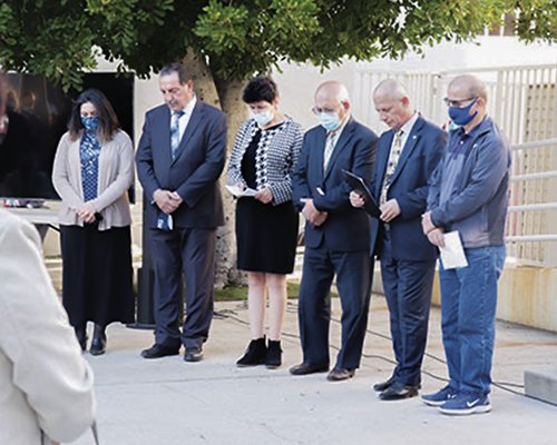 Group of people in formal attire praying.