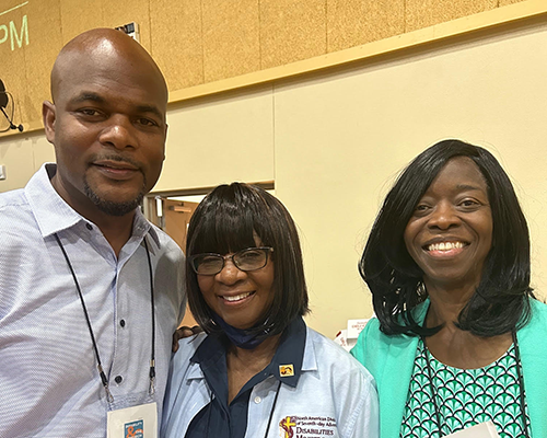 A black man and two black women in business casual at a conference