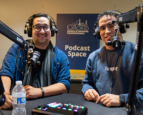 Two young men pose at the SAC Podcast station at 2024 convention 