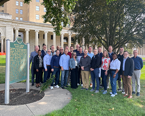 A group of men and women stand in front of the Battle Creek Sanitarium