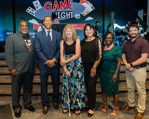 A diverse group of men and woman stand in front of a church sanctuary