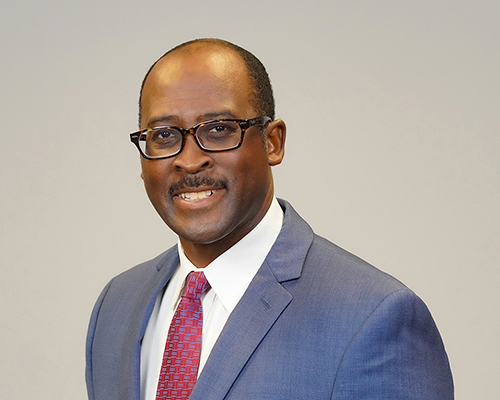 Headshot of a smiling black man in a suit