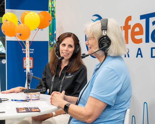 Two women sit with headsets on at the life-talk radio booth during the GC session..