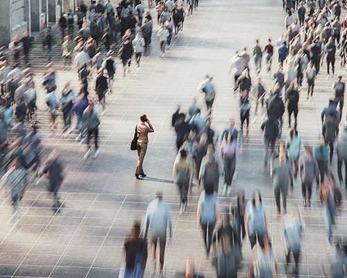 business woman stopped in a blurry sea of moving people walking around her