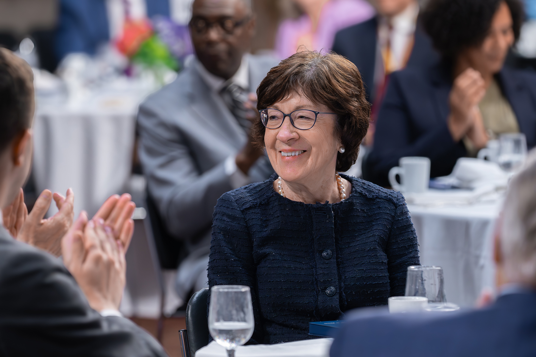 Close-up of a smiling white woman seated at a dinner table 