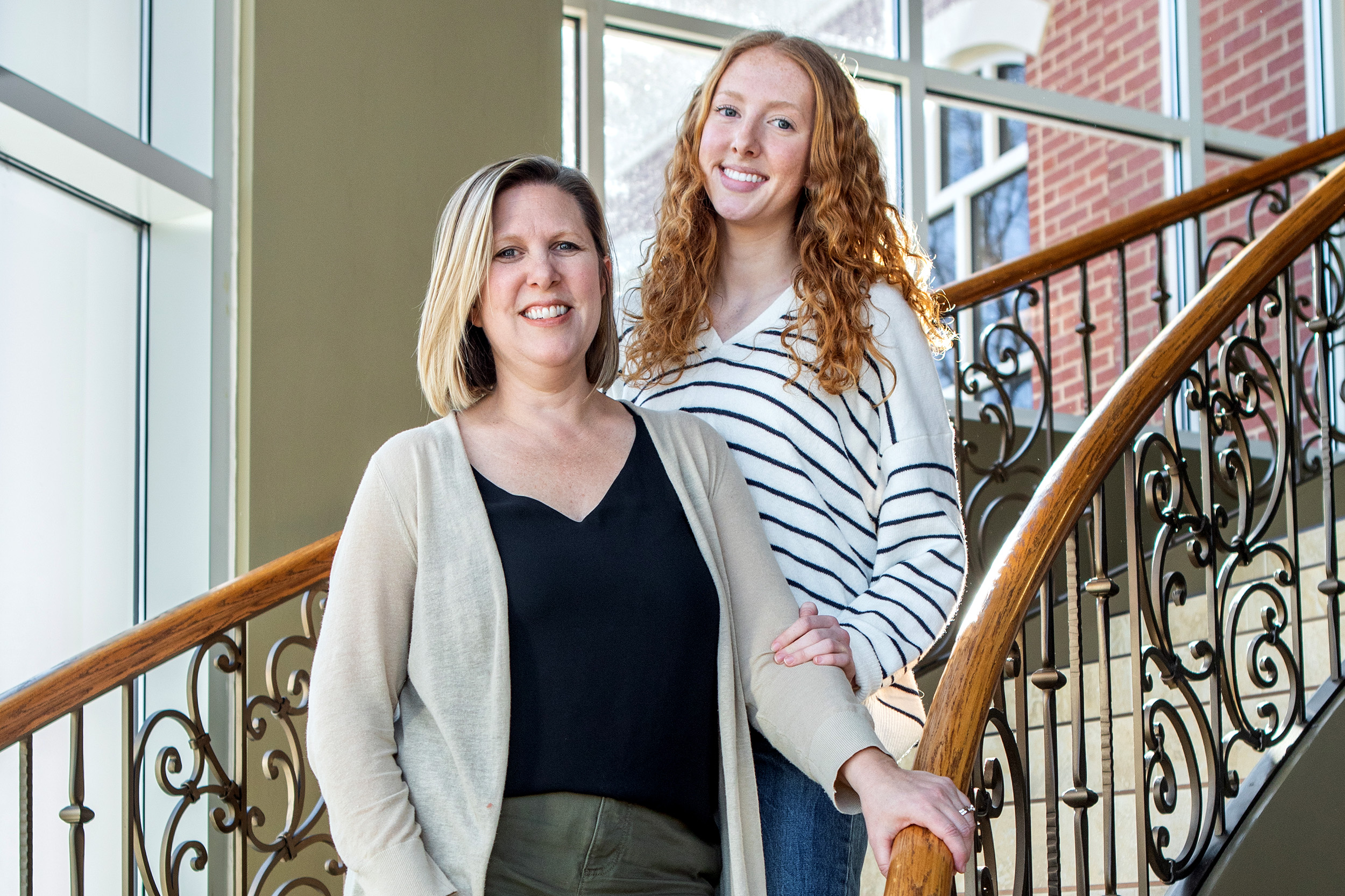 Two women, one blonde and one red-headed, smiling towards camera.