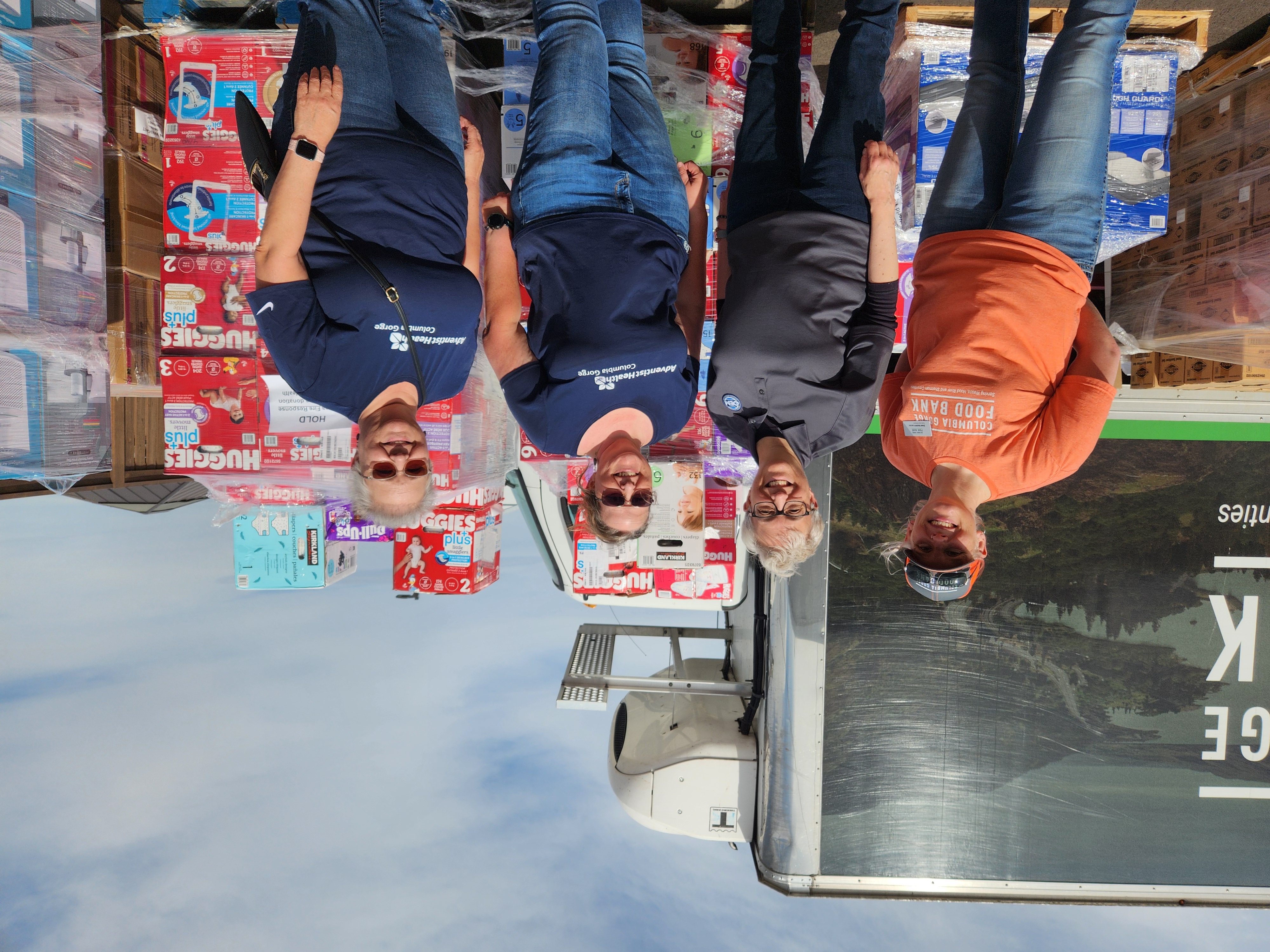 Volunteers stand in front of donations at distribution center.