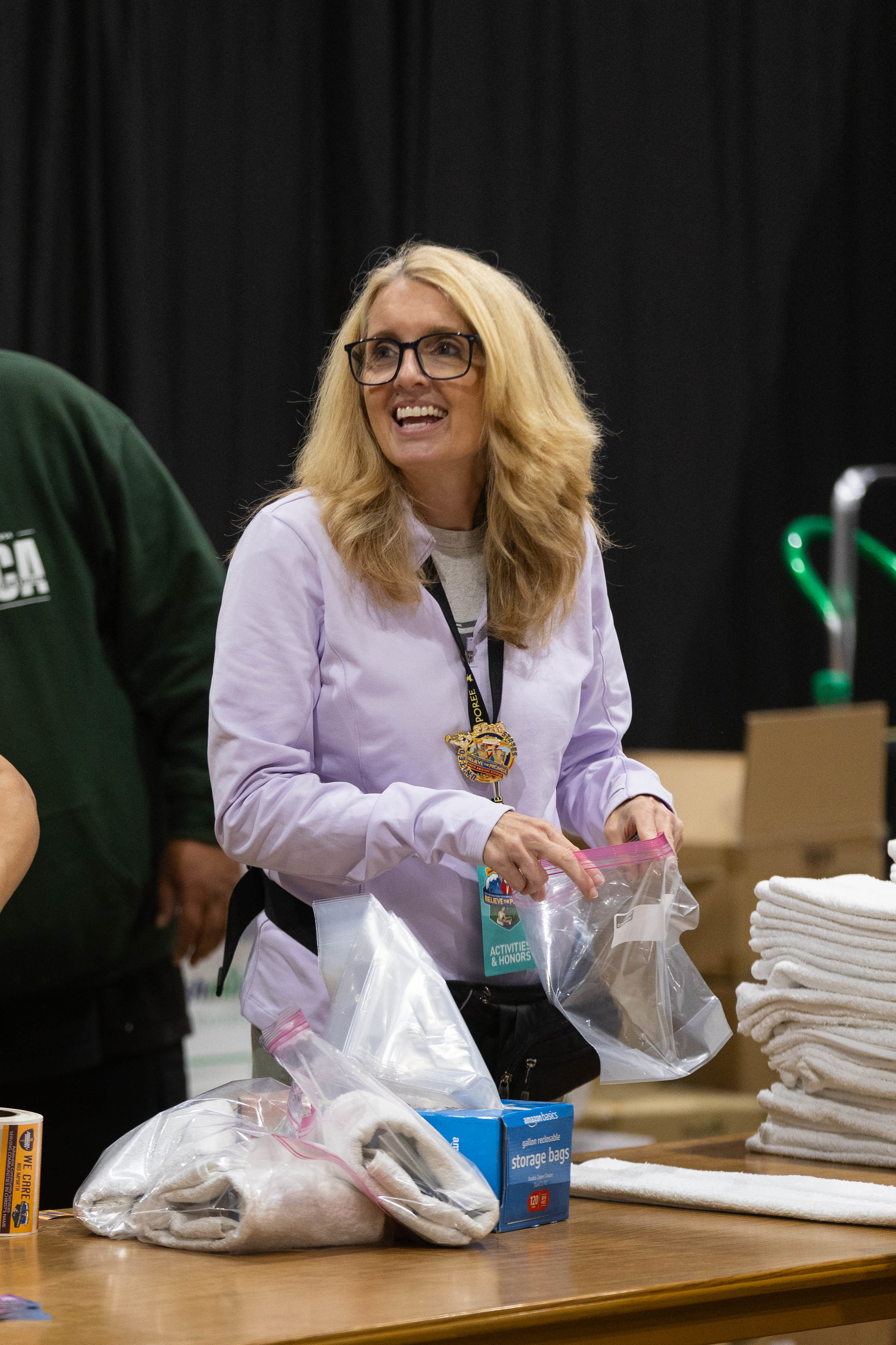  A smling woman with a Ziploc bag in her hand, creating a hygiene kit for the community. 
