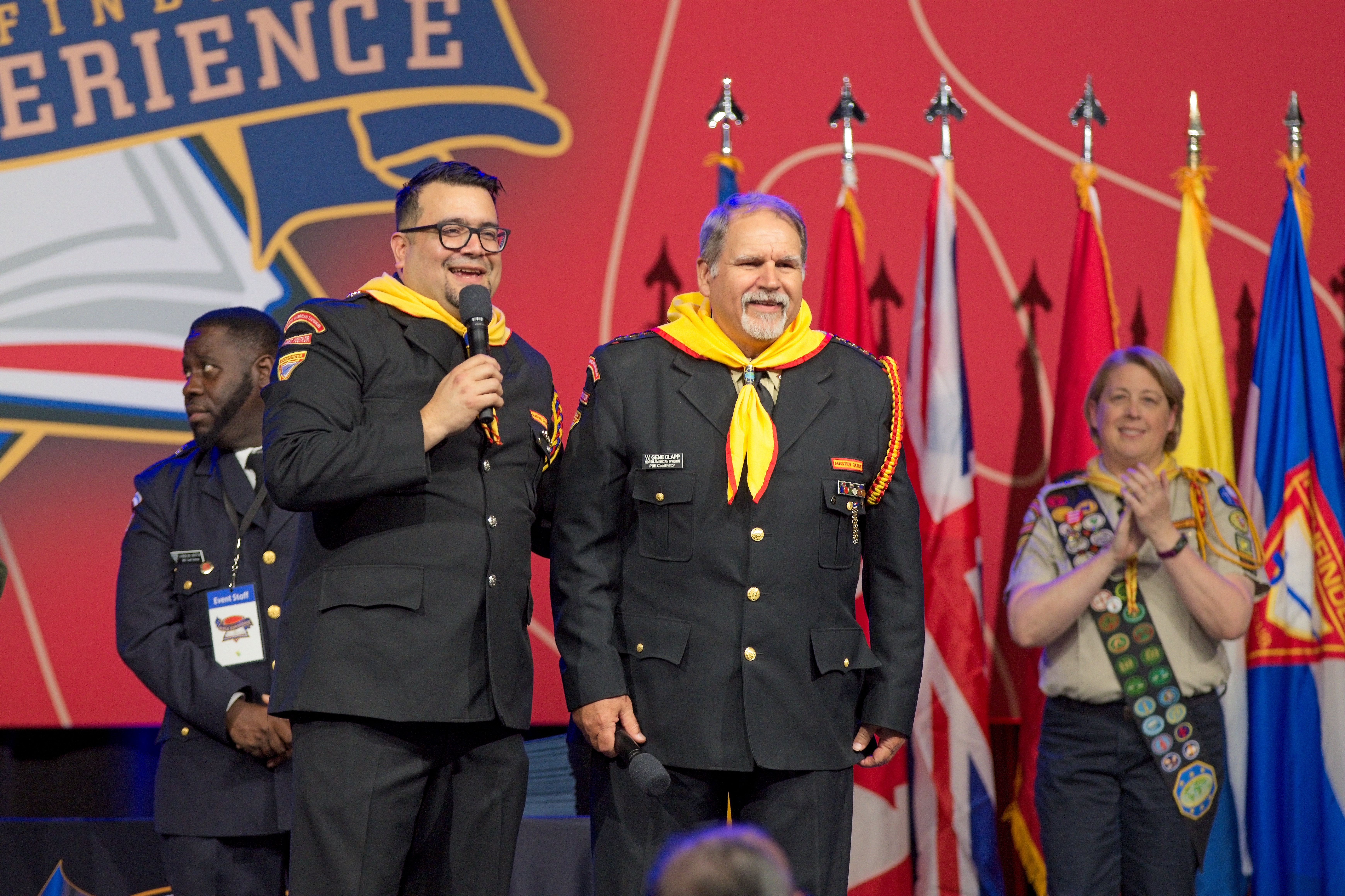 Adult Pathfinder leaders in uniform speak on stage