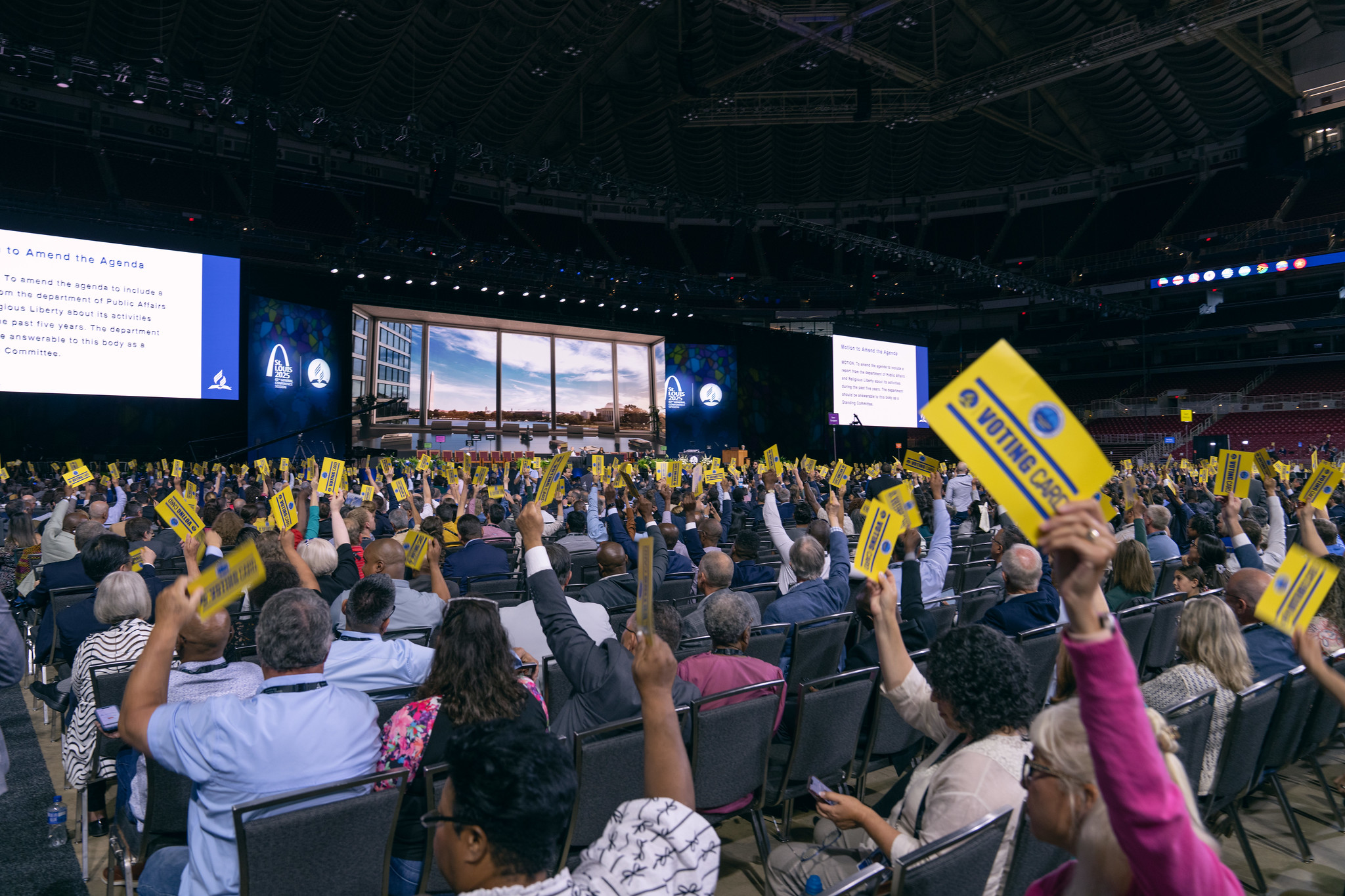 Delegate at the GC Session Floor hold up their voting cards.