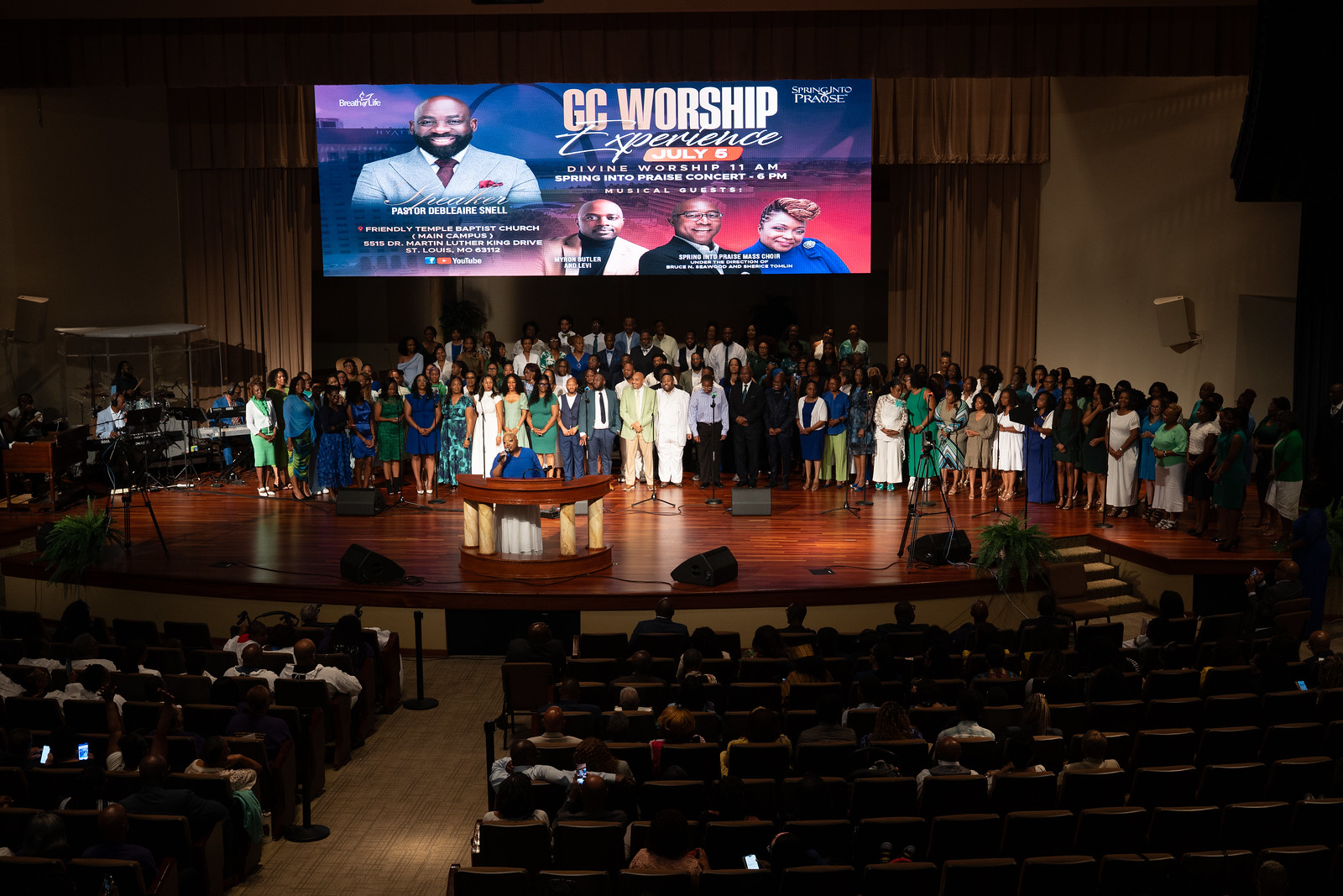 Gospel choir and artist Myron Butler sing on the stage of the church.