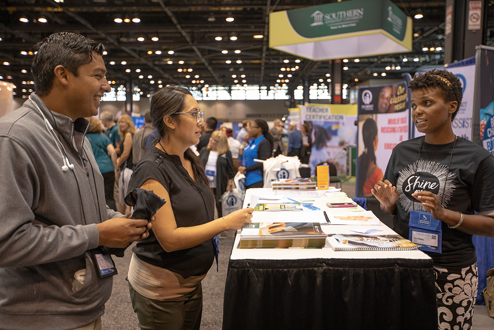 A representative of Encounter Bible Series discusses the organization’s resources with two attendees of the 2018 NAD Teachers’ Convention. 