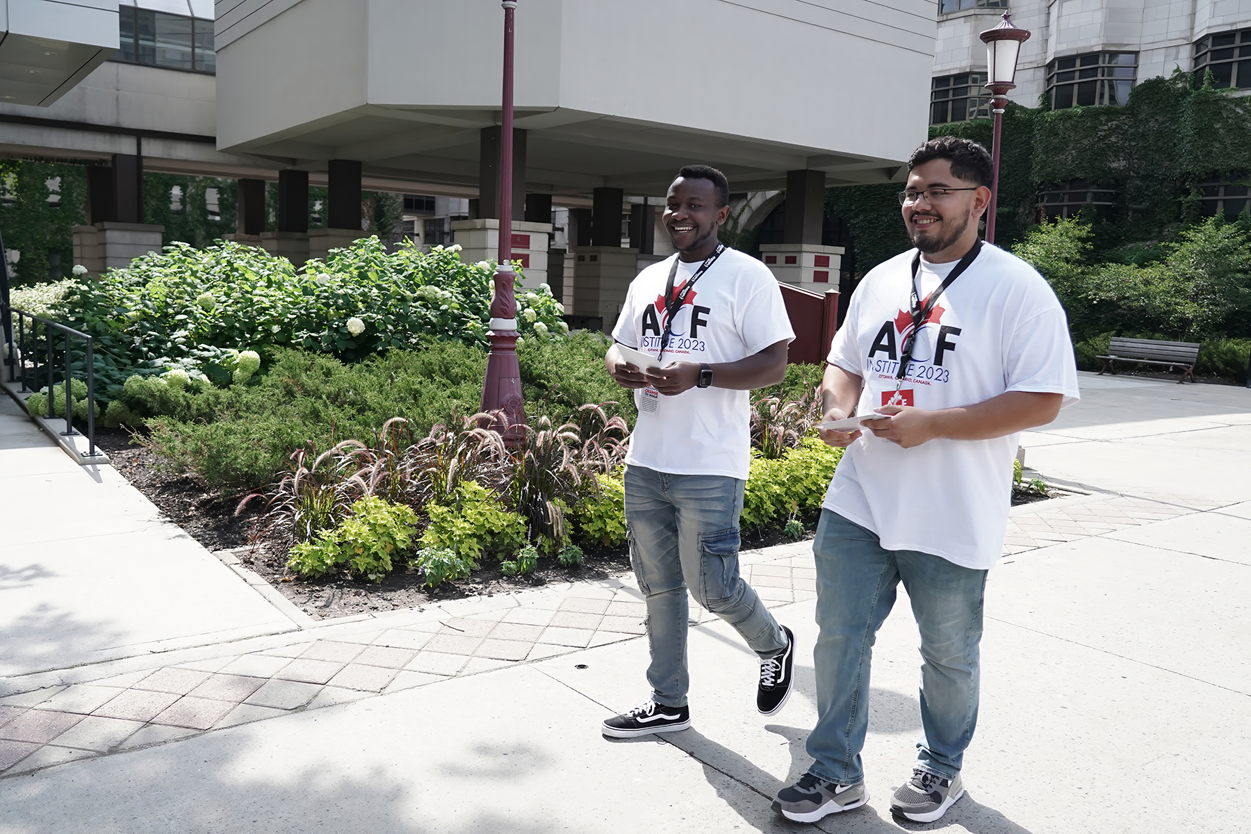 Two young men, one black, one Hispanic, wearing matching white tshirts and jeans.
