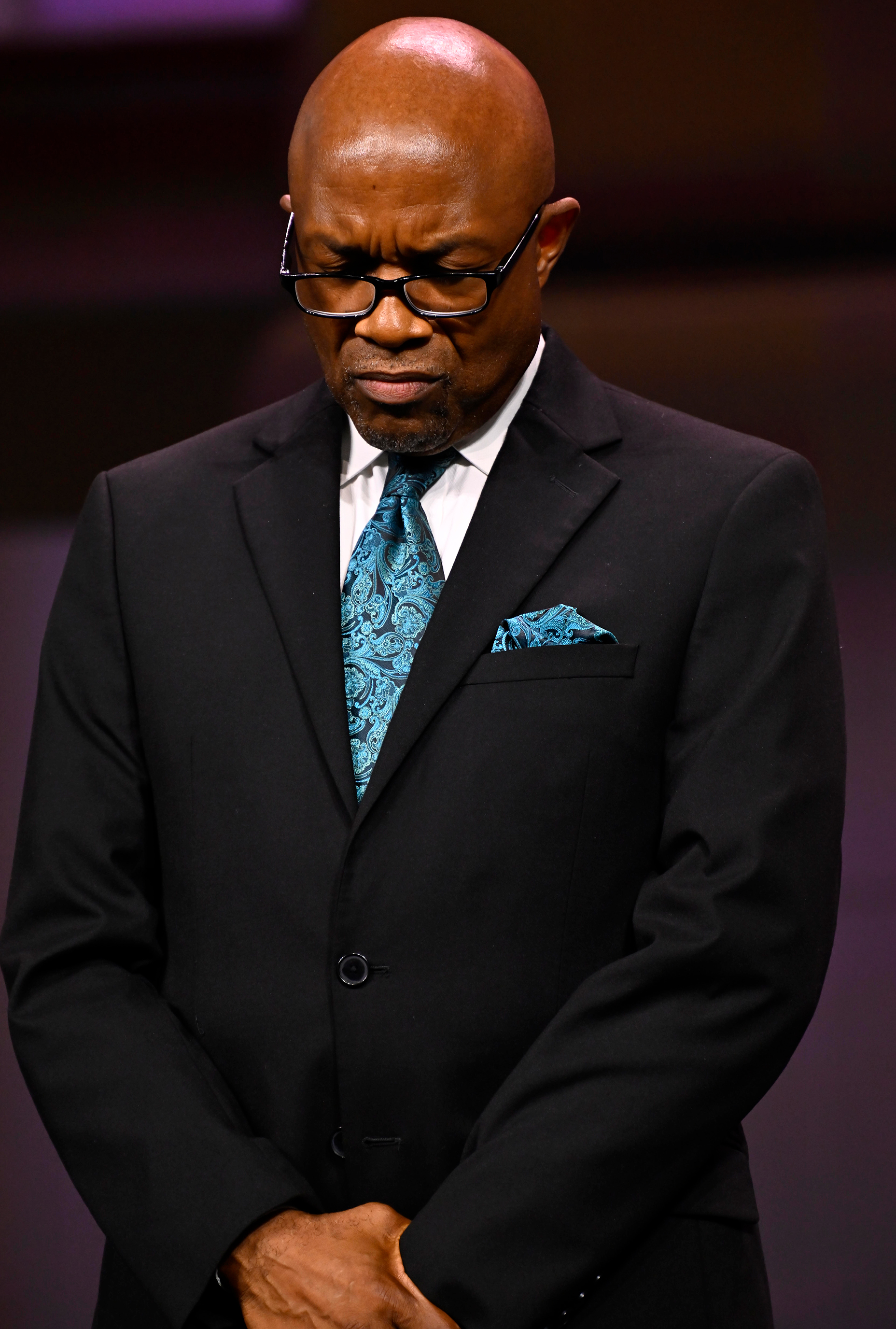 Black man in a suit praying