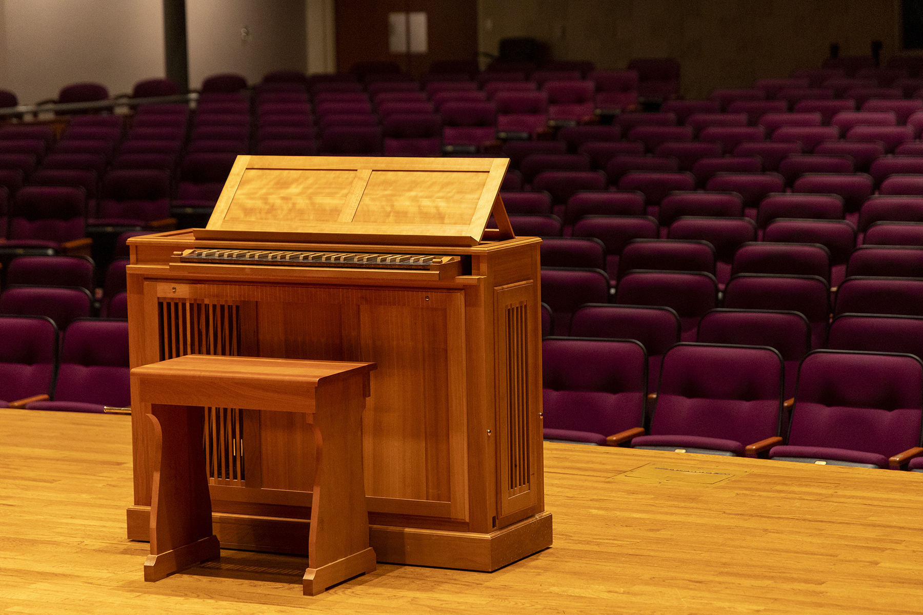 A wooden organ shines in the light of the stage at Andrew's University