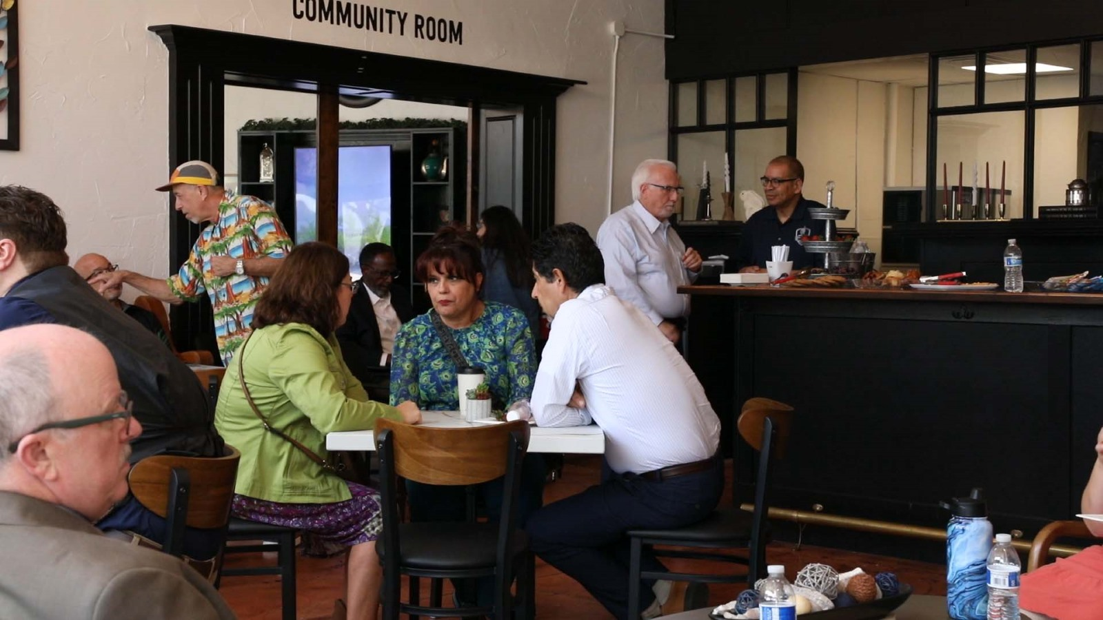 A group of three chatting inside a crowded bread and better life cafe.