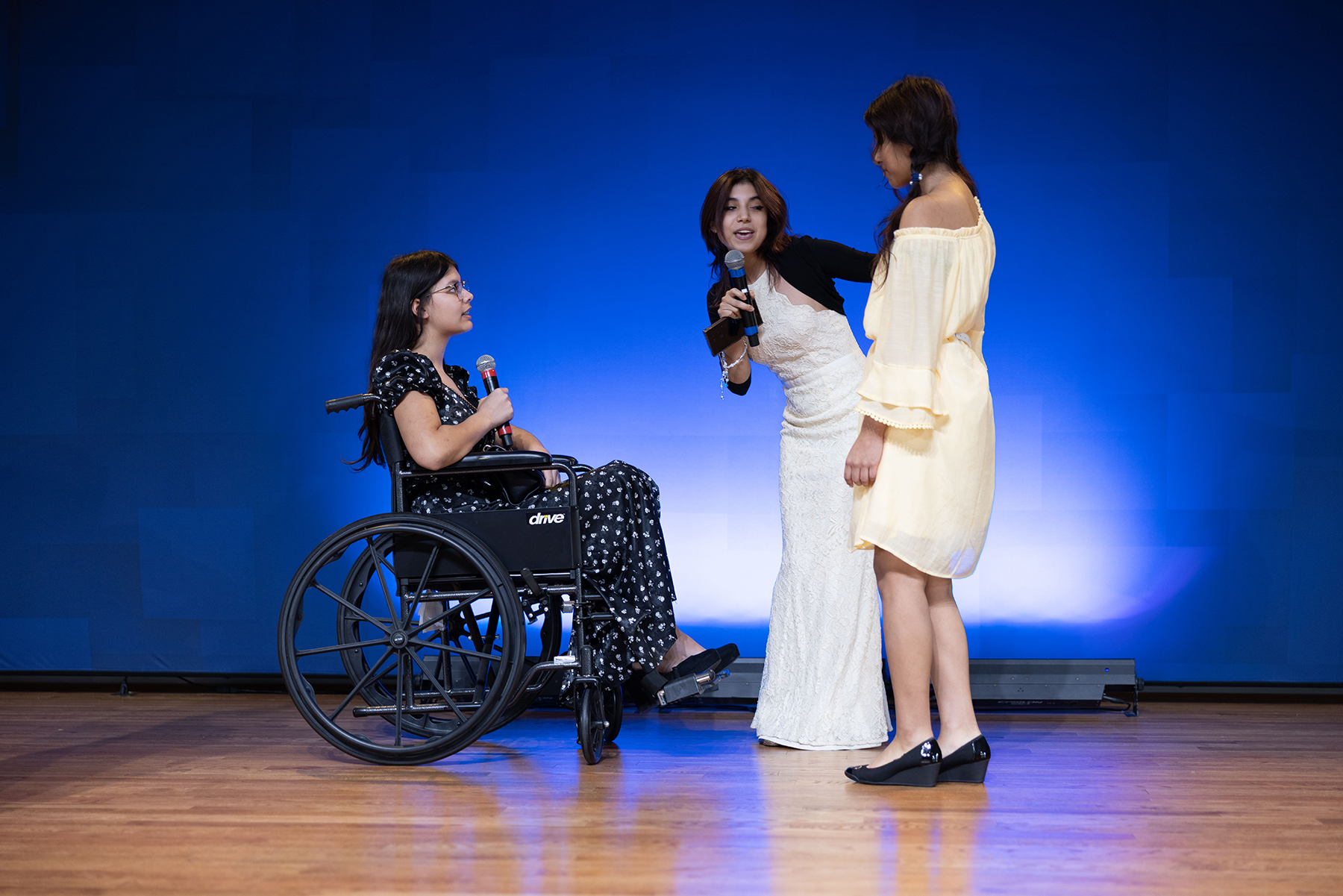 Three young women, one in a wheelchair and the other two standing up