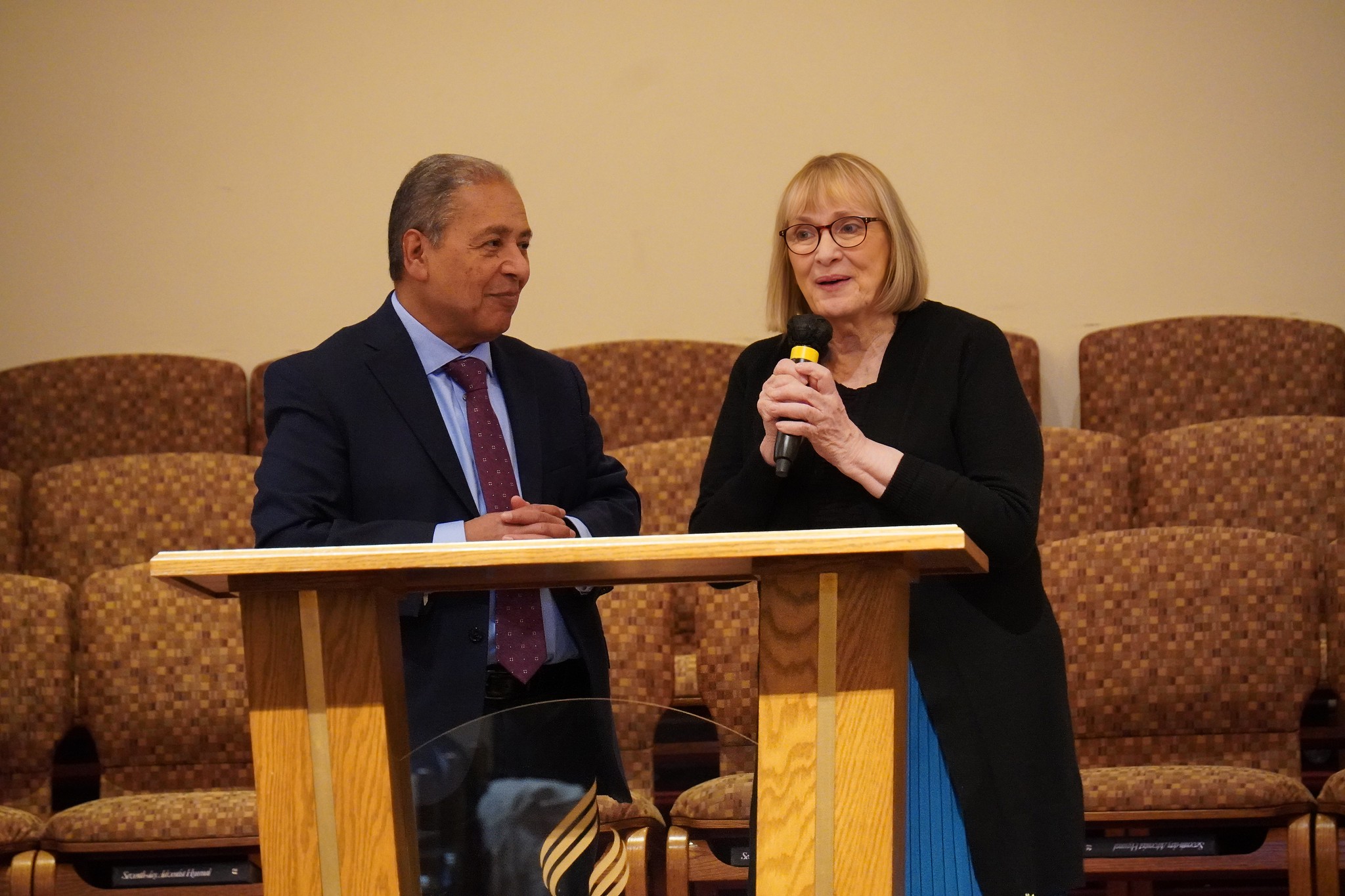 Middle age Latino man and caucasian middle age woman speak to a group