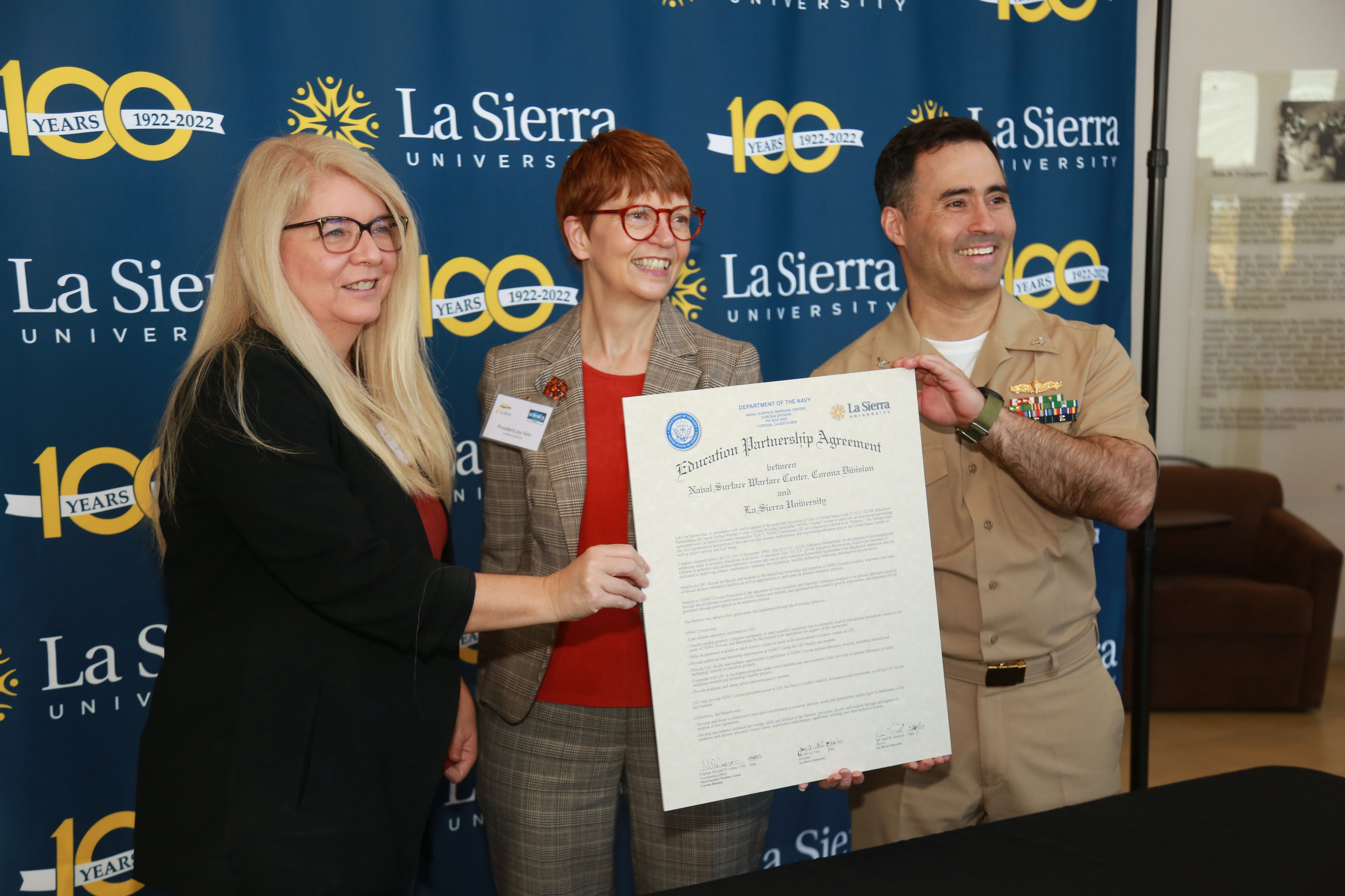 La Sierra University provost April Summitt, La Sierra University president Joy Fehr, and NSWC Corona commanding officer Capt. Michael Aiena hold a commemorative version of the Educational Partnership Agreeement after signing it on Nov. 14. 