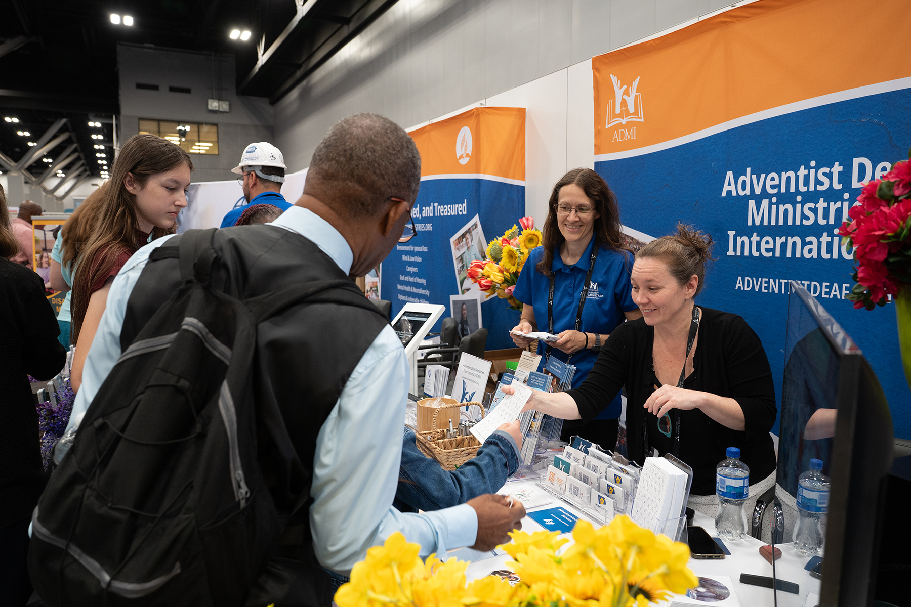 Two women engage with visitors at a booth