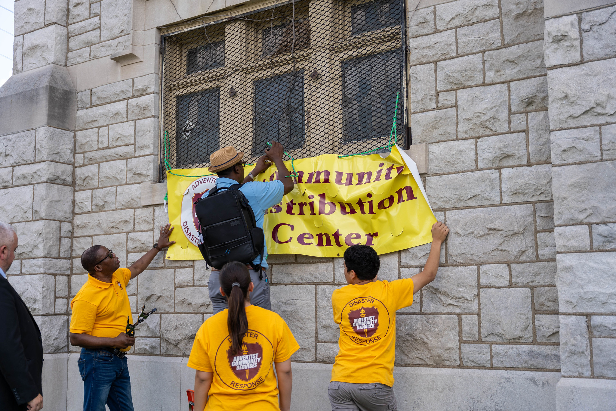 ACS leaders and youth volunteers hang up a "Community Distribution Center" banner on the side of the St. Louis Spanish Seventh-day Adventist Church so residents can find it easily.