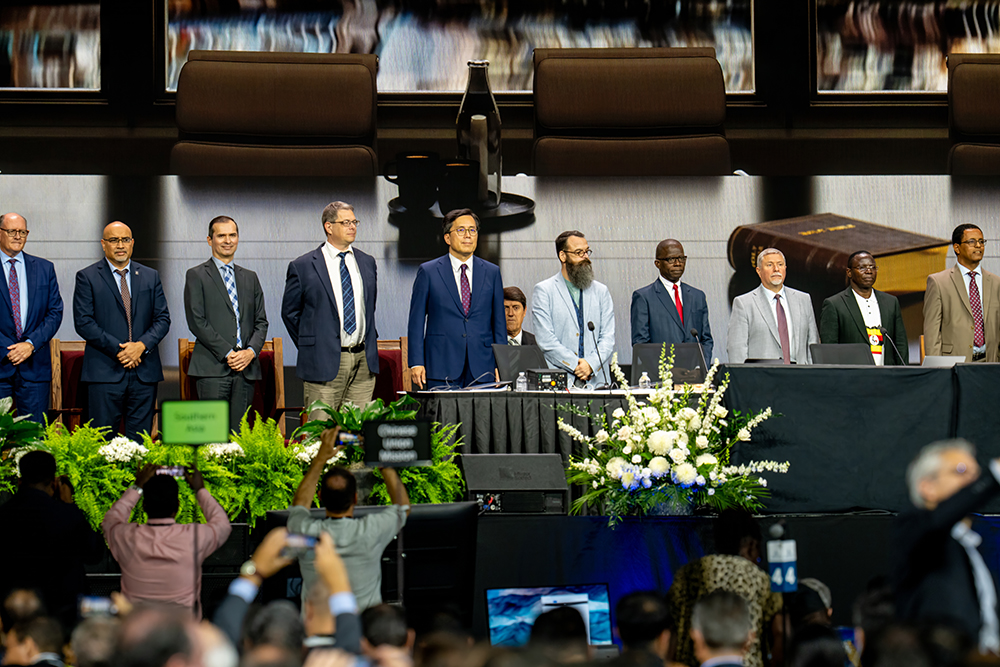 A diverse group of men in suits stand on a stage