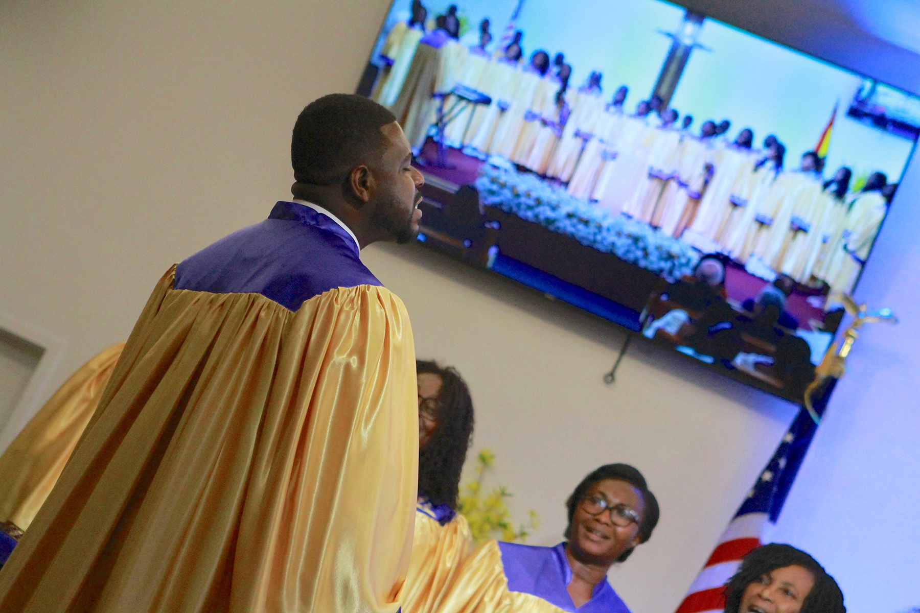 Close-up of Ghanaian choir in robes with image of full choir visible on a screen 