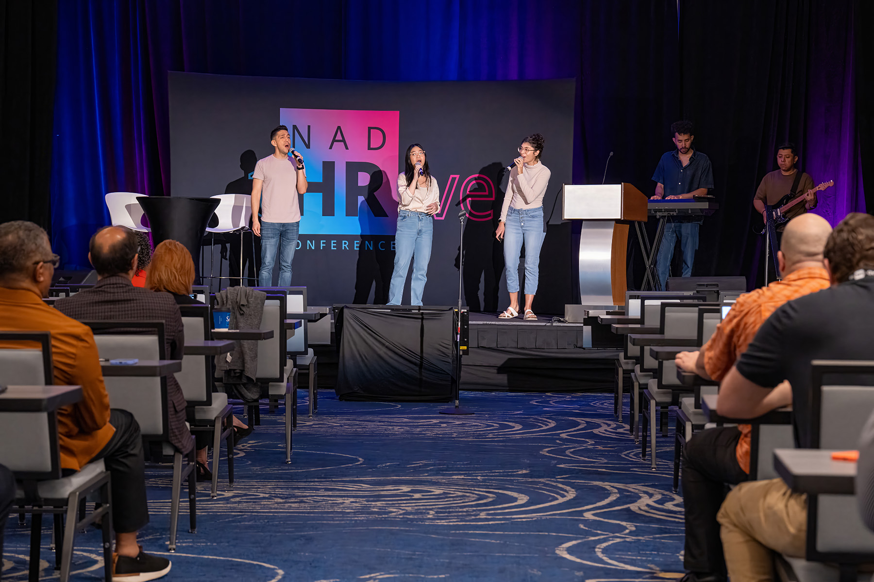 A praise team sings in front of an auditorium full of people