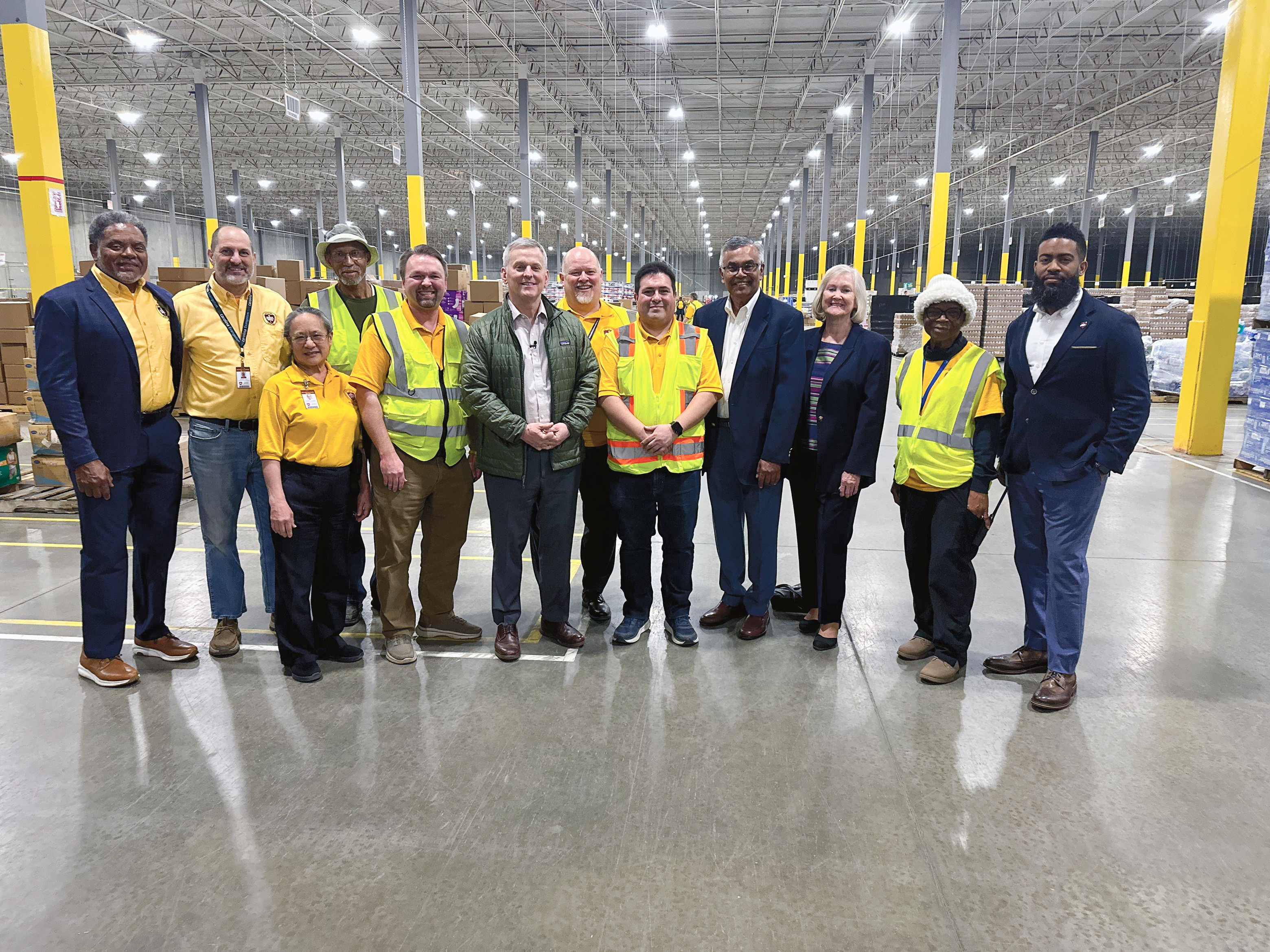 Diverse group of men and woman pose in a warehouse