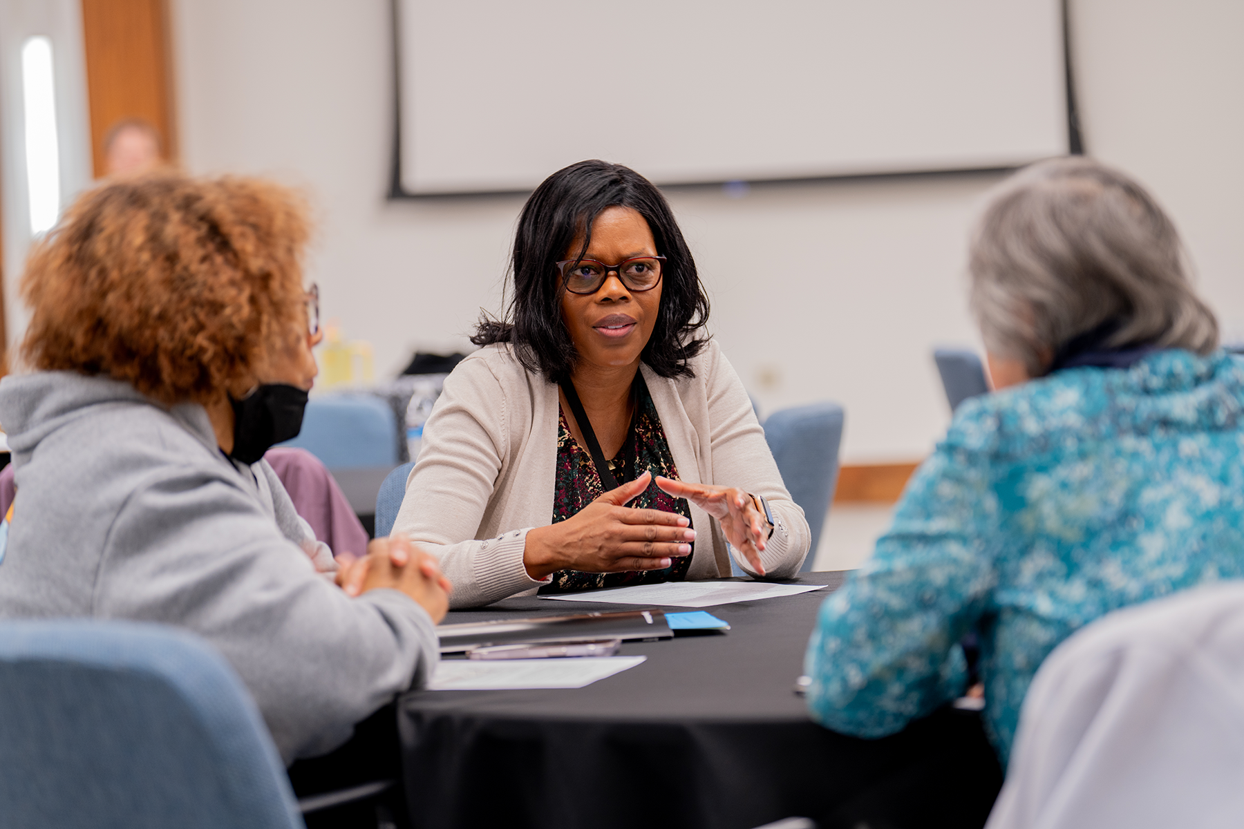 Close-up of diverse group of three women speaking, woman in middle in sharp focus. 