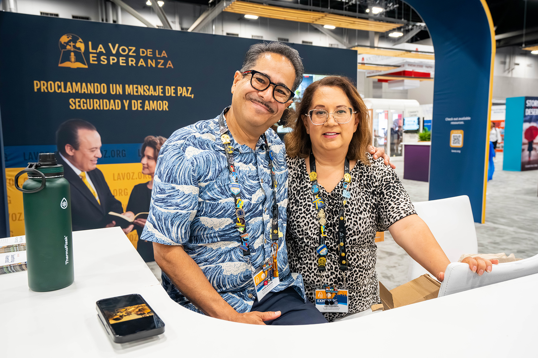 Smiling man and woman at La Voz De La Esperanza exhibit