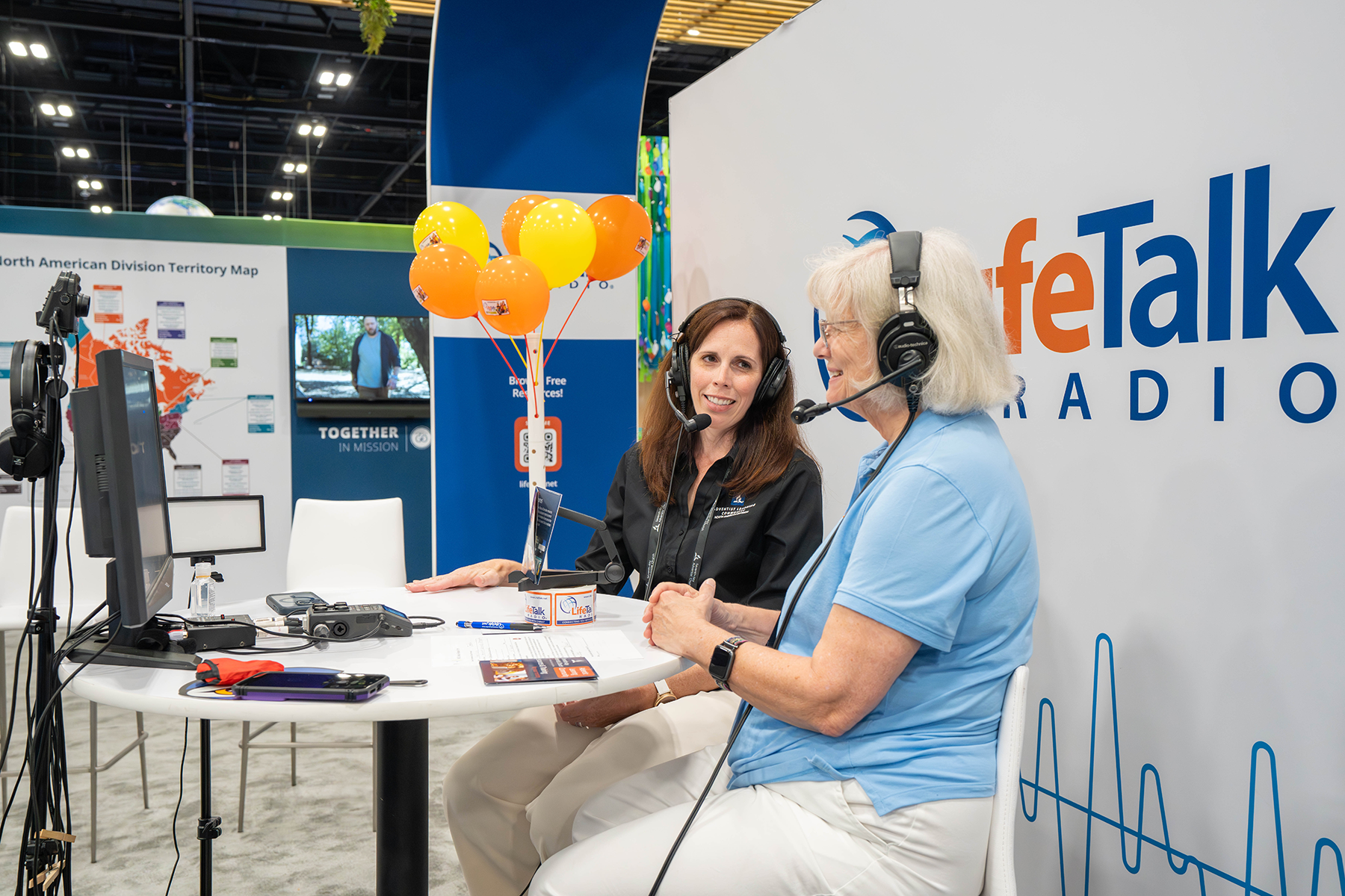 Two women doing a podcast in an exhibit hall