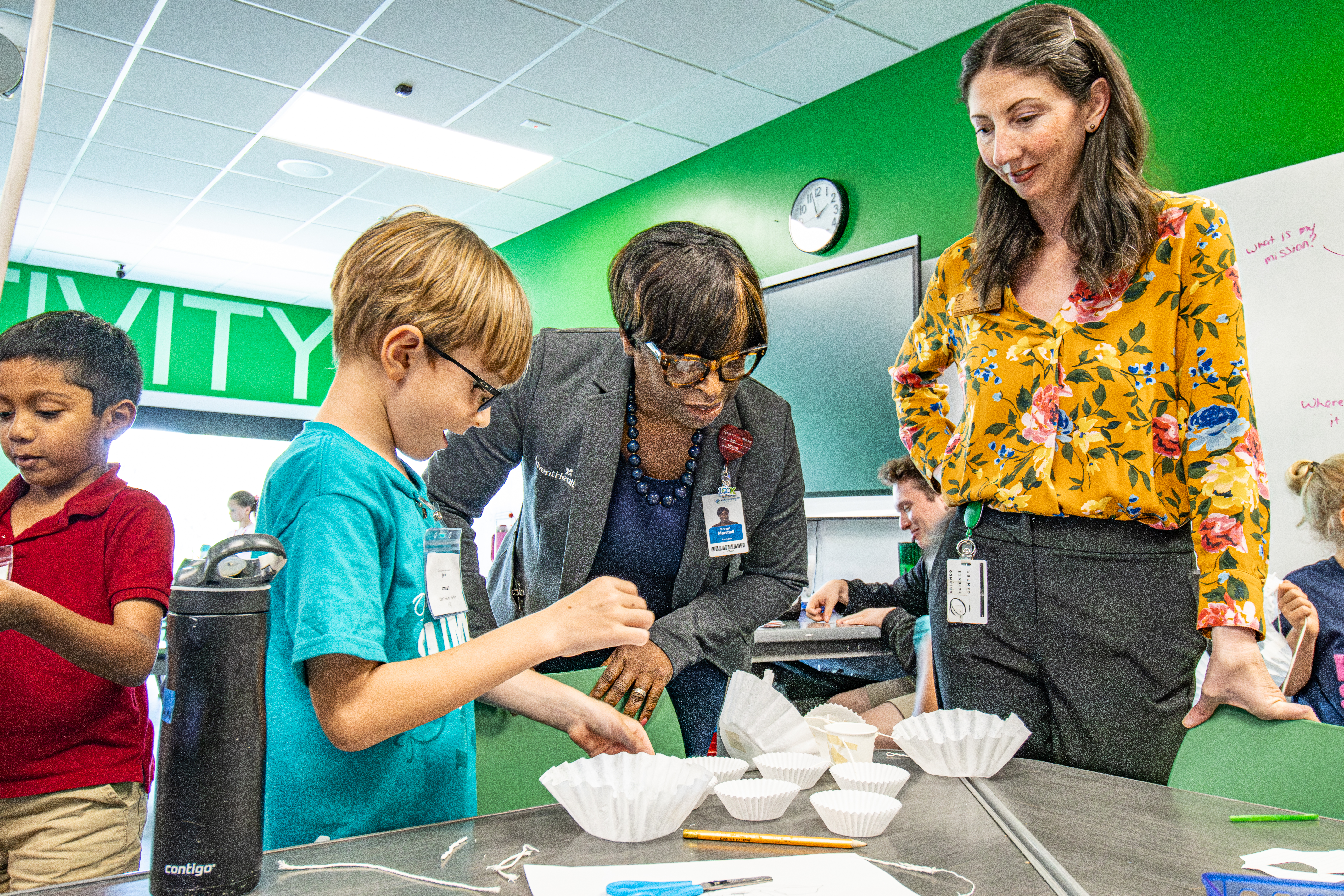 An Adventhealth representatives learns about science concepts with students.