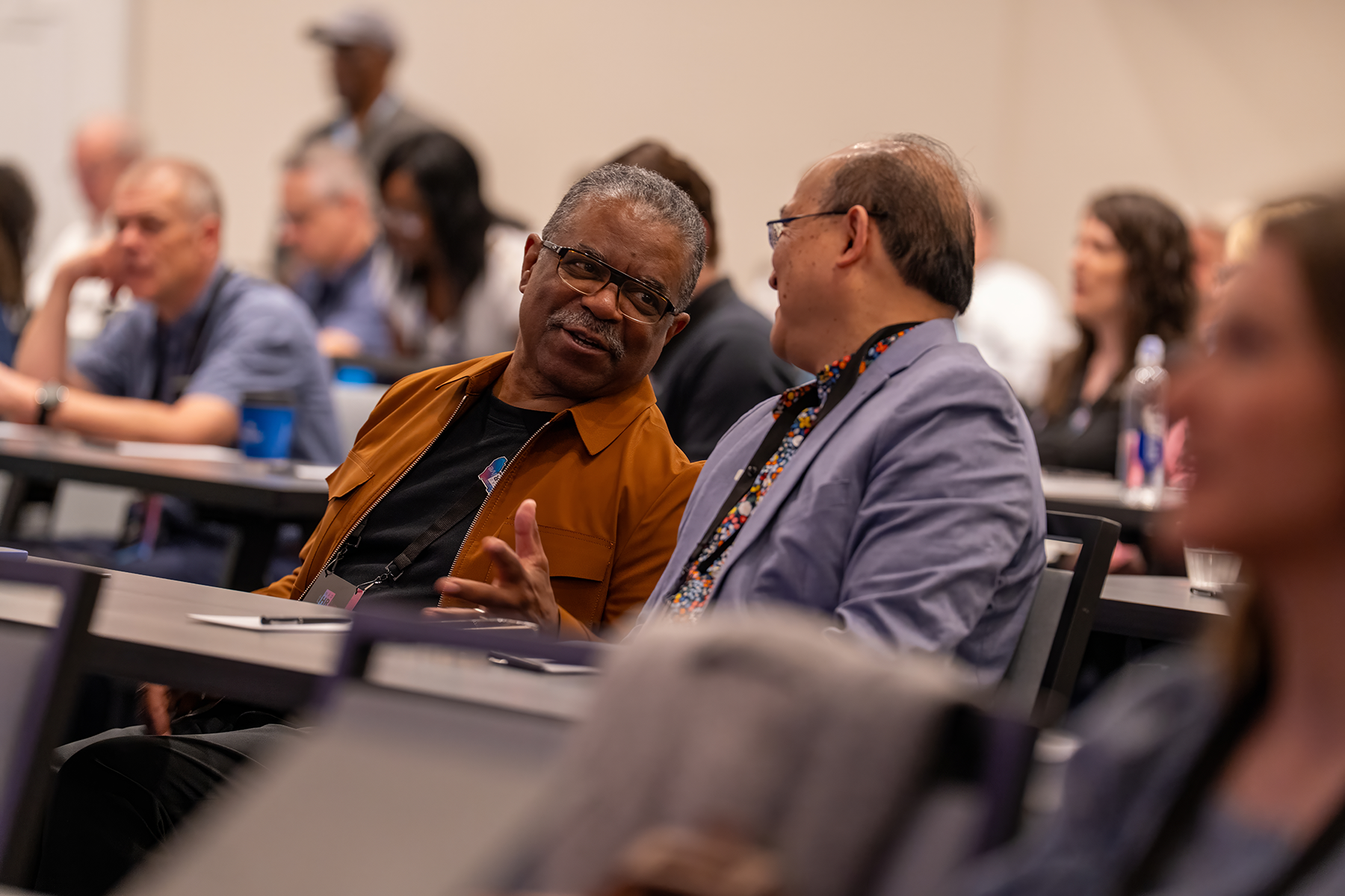 Two men chat in the midst of a packed room