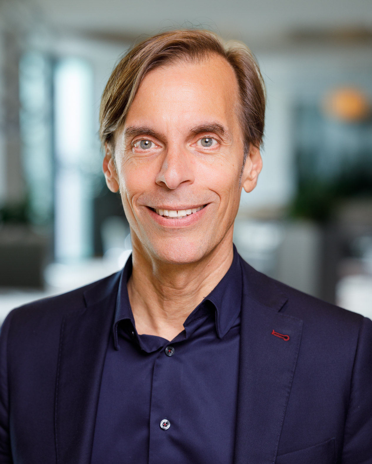 Man in business attire smiling towards camera.