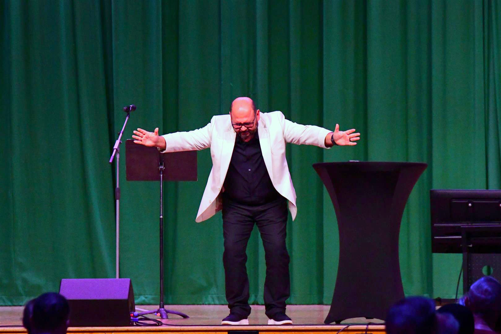 Robert Cornado, pastor of the Chattanooga Hispanic Community Seventh-day Adventist Church, spreads his arms in reverence on stage during prayer.
