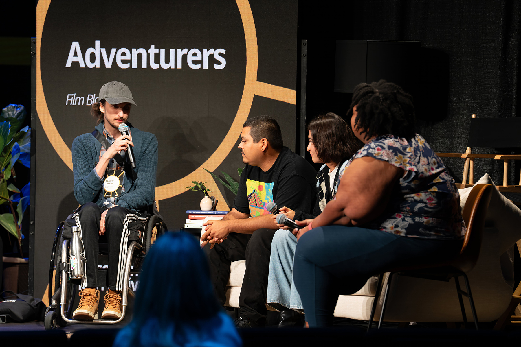 A man in a wheelchair speaks to three other people on Sonscreen stage. 